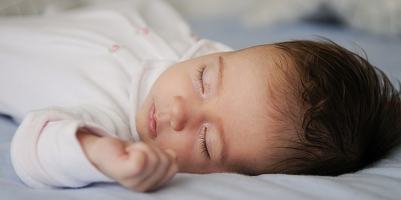 newborn-baby-girl-sleeping-blue-sheets-home